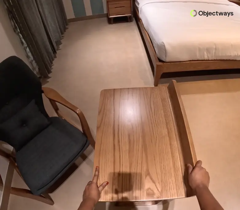 A clear first-person or egocentric view of a person's hands opening a drawer on a wooden table inside a modern bedroom