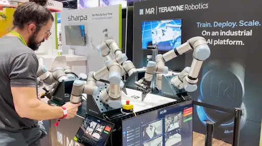 A person interacts with a dual-arm collaborative robot (cobot) system at a Teradyne Robotics trade show booth