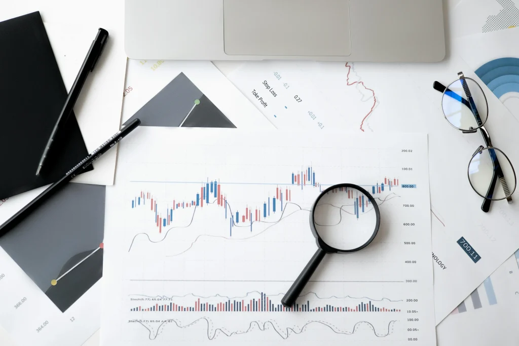 Overhead view of financial charts, a laptop, glasses, and a magnifying glass used for data auditing