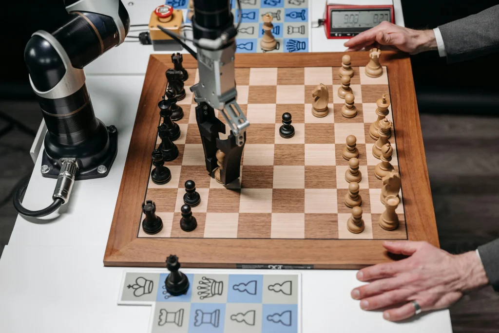 A robotic arm plays a game of chess against a human, moving a piece on the board, demonstrating AI strategy and precision