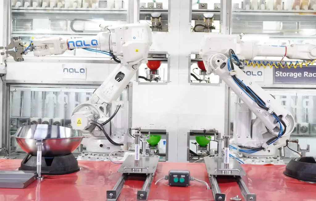 Two robotic arms working in an automated commercial kitchen, showcasing the use of robotics in food preparation and service