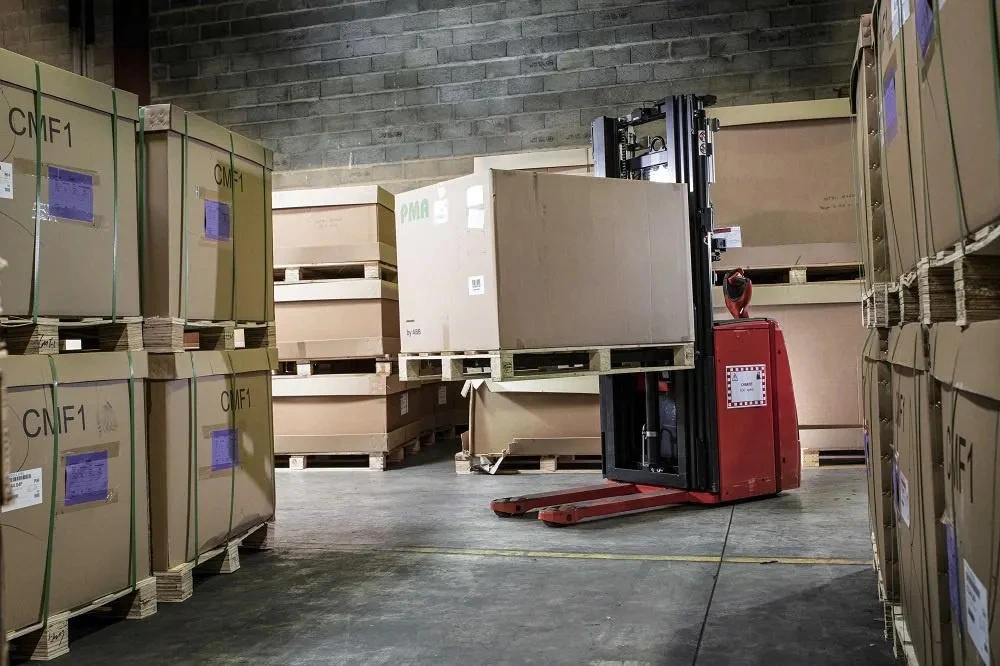 An autonomous forklift moving a pallet with a large box in a warehouse, demonstrating automation in supply chain and logistics