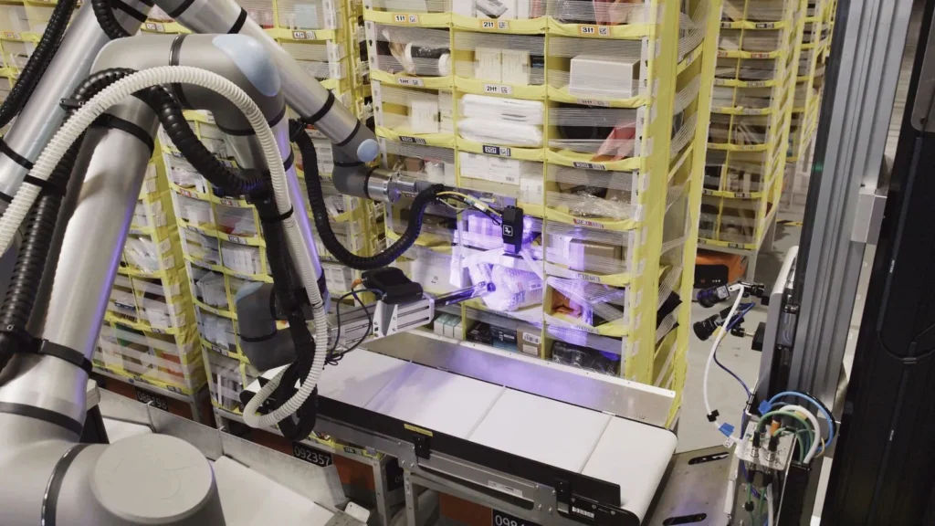 Robotic gripper arm selecting a package from yellow storage pods in a fulfillment warehouse