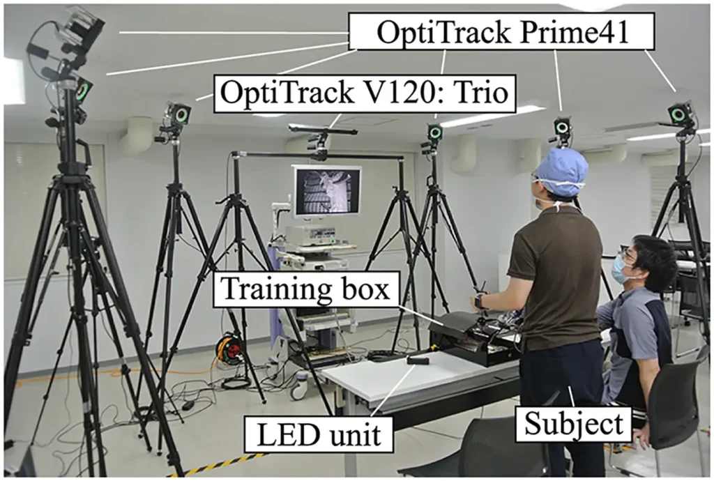 Laboratory setup featuring OptiTrack motion capture cameras tracking a subject in a medical simulation