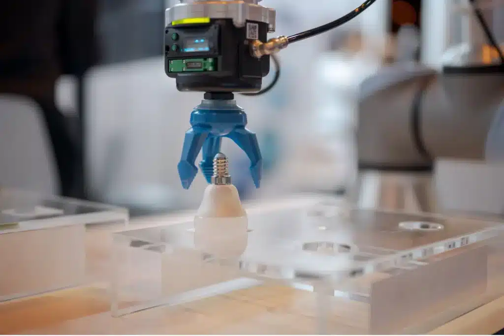 Precision robotic gripper holding a delicate lightbulb, showcasing automation in industrial assembly