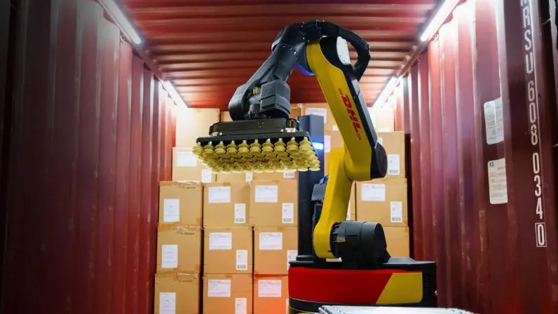 Boston Dynamics Stretch robot using a suction gripper to unload stacked boxes inside a DHL shipping container